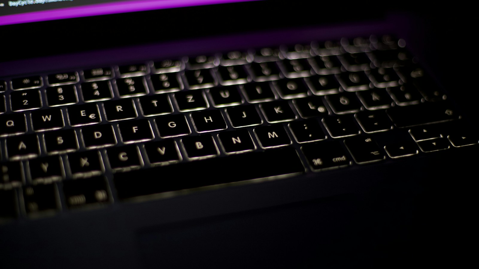 Detail papan ketik laptop dalam pencahayaan gelap.